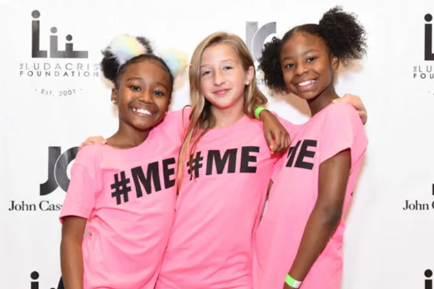 Three girls wearing pink t-shirts that read '#ME'.